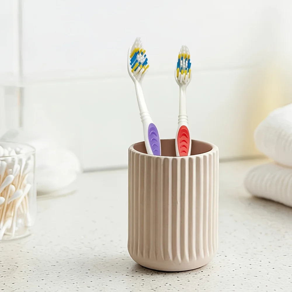 A beige cylindrical container holds two toothbrushes, one blue and yellow, and one blue and white.