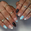 Close-up of hands displaying various nail art designs including pink, white, and blue stripes and glitter accents