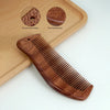 A wooden scalp and hair comb set featuring a reddish-brown wood grain and a round hole design on a light wooden cutting board