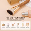A gold-toned angled contour makeup foundation brush shown next to various cosmetic products for liquid or powder foundation a