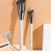 A set of two professional makeup brushes with silver ferrules and light wood handles displayed against a beige background.