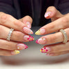 Close-up of hands displaying pink cat eye false nails with 3D floral and butterfly designs
