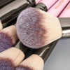 A close-up of a professional makeup brush with silver ferrule and a fluffy, gradient brush head.