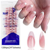 A hand displays soft gel tips for artificial fingernails in a standard size package with pink and white nail designs.