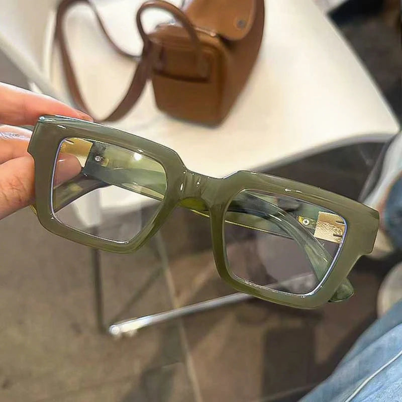 Lunettes à monture carrée rétro vert olive avec cadre fin et branches visibles sur fond clair