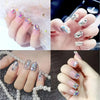 A hand displays various mixed glass rhinestones and nail art designs on fingernails.
