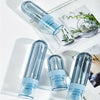 Clear blue portable refillable fine mist spray bottles displayed on a white surface with natural greenery.