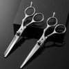 A pair of professional silver haircutting scissors set resting on a dark surface.