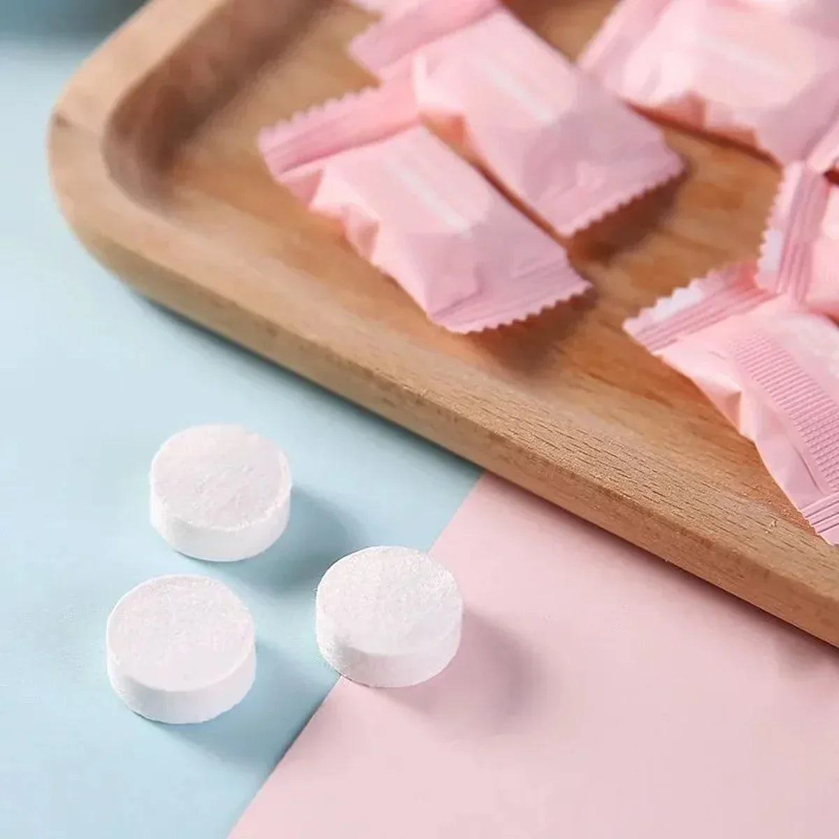 Pink disposable wet wipes are arranged on a wooden board next to white wipes and pink paper.
