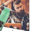A bearded man is using a professional cordless hair clipper trimmer to style his hair.