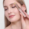A woman is using a pink electric eyebrow trimmer on her upper lip.