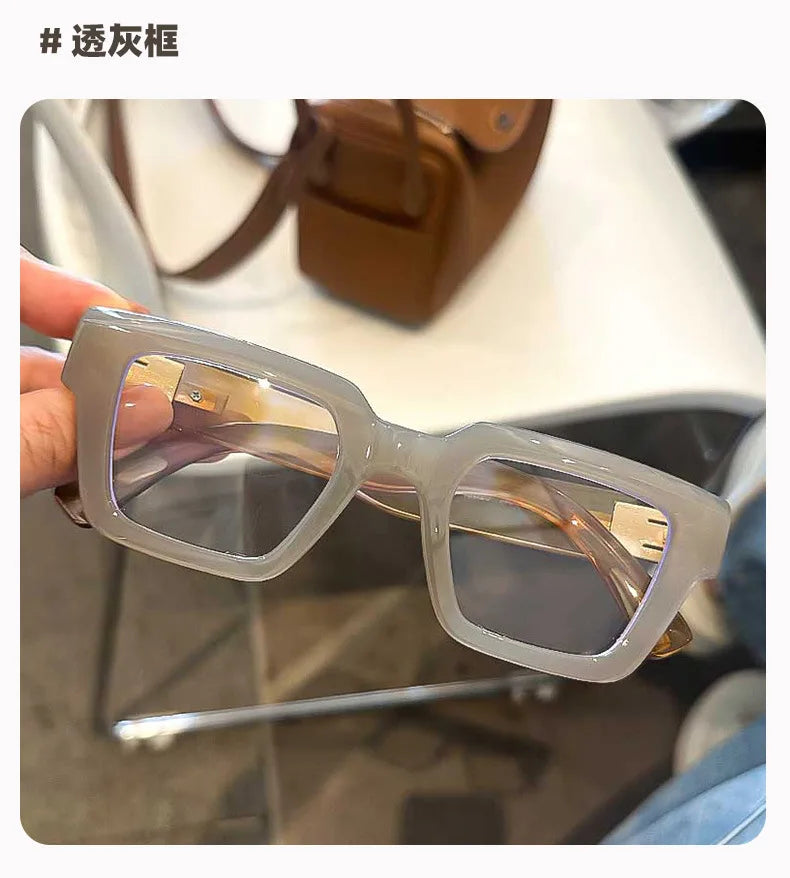 Une paire de lunettes de lecture carrées et transparentes avec des verres ambrés posées sur une surface.