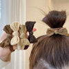 Una mano sostiene un juego de diez gomas para el pelo de colores beige y marrón para coletas.