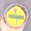 A yellow silicone makeup puff set with a single white tulip flower inside a clear storage box.