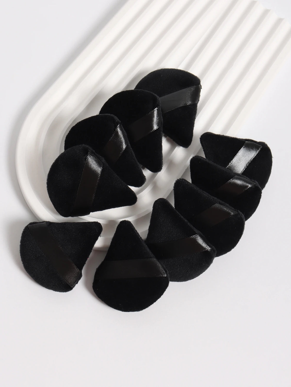 Un ensemble de tampons de poudre noirs triangulaires disposés sur un plat blanc.