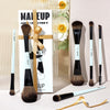 A set of six vegan fiber makeup brushes displayed in a box with natural light and floral accents.