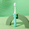 A light blue dinosaur-themed toothbrush standing upright on a green surface.