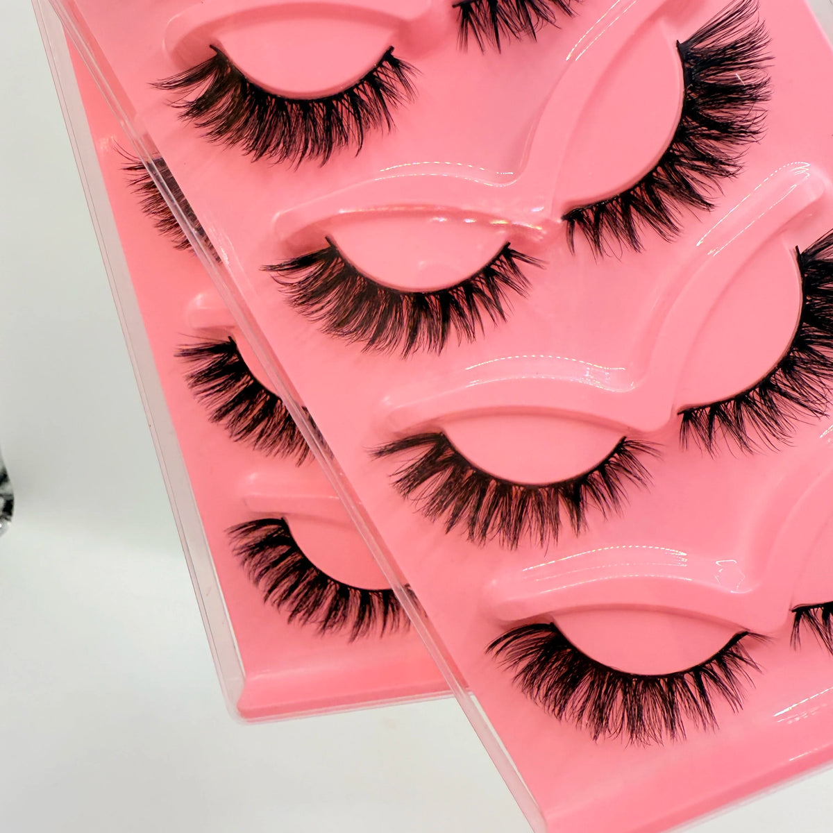 Un plateau en plastique rose contenant cinq paires de faux cils noirs dramatiques.