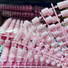 A close-up of pink French press on toenails used for summer decor, showing various nail designs.
