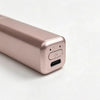 A close-up view of a rose gold portable wireless hair comb and curling iron device.