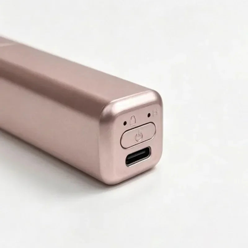 A close-up view of a rose gold portable wireless hair comb and curling iron device.