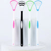 Three silicone tongue cleaners in pink, black, and green are displayed on a white stand.