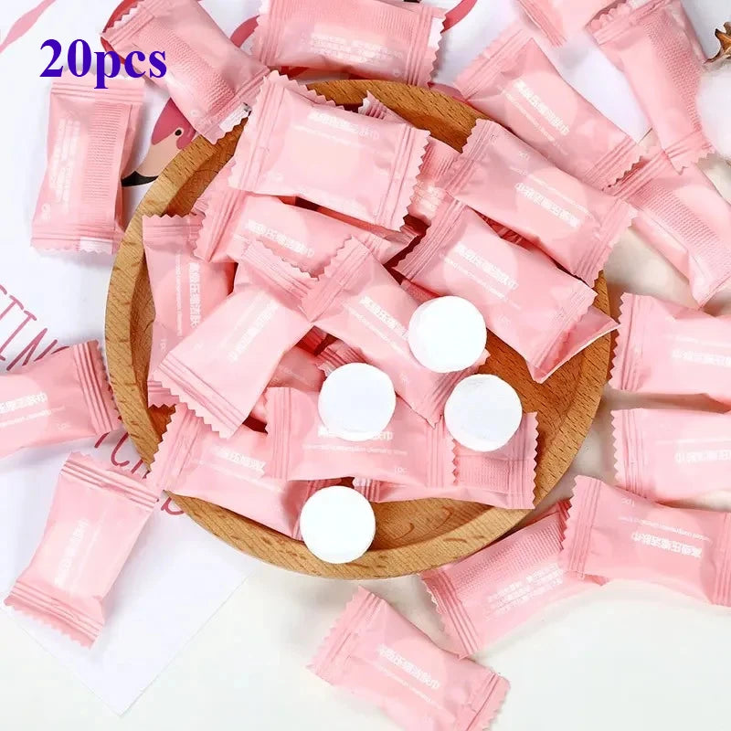 A pile of 20 pink disposable wet wipes are arranged on a wooden surface.