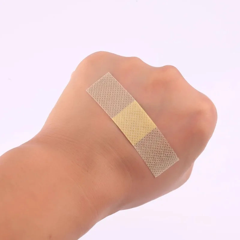 A hand holds a sterile waterproof hemostatic adhesive patch on the wrist.