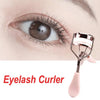 Un recourbe-cils rose avec une brosse à côté d'un œil pour recourber les cils.