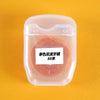 A clear plastic container holds a spool of orange colored 50 meter disposable nylon dental floss.