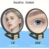 A portable dual-sided makeup mirror showing a woman's face and an eye magnified 30 times