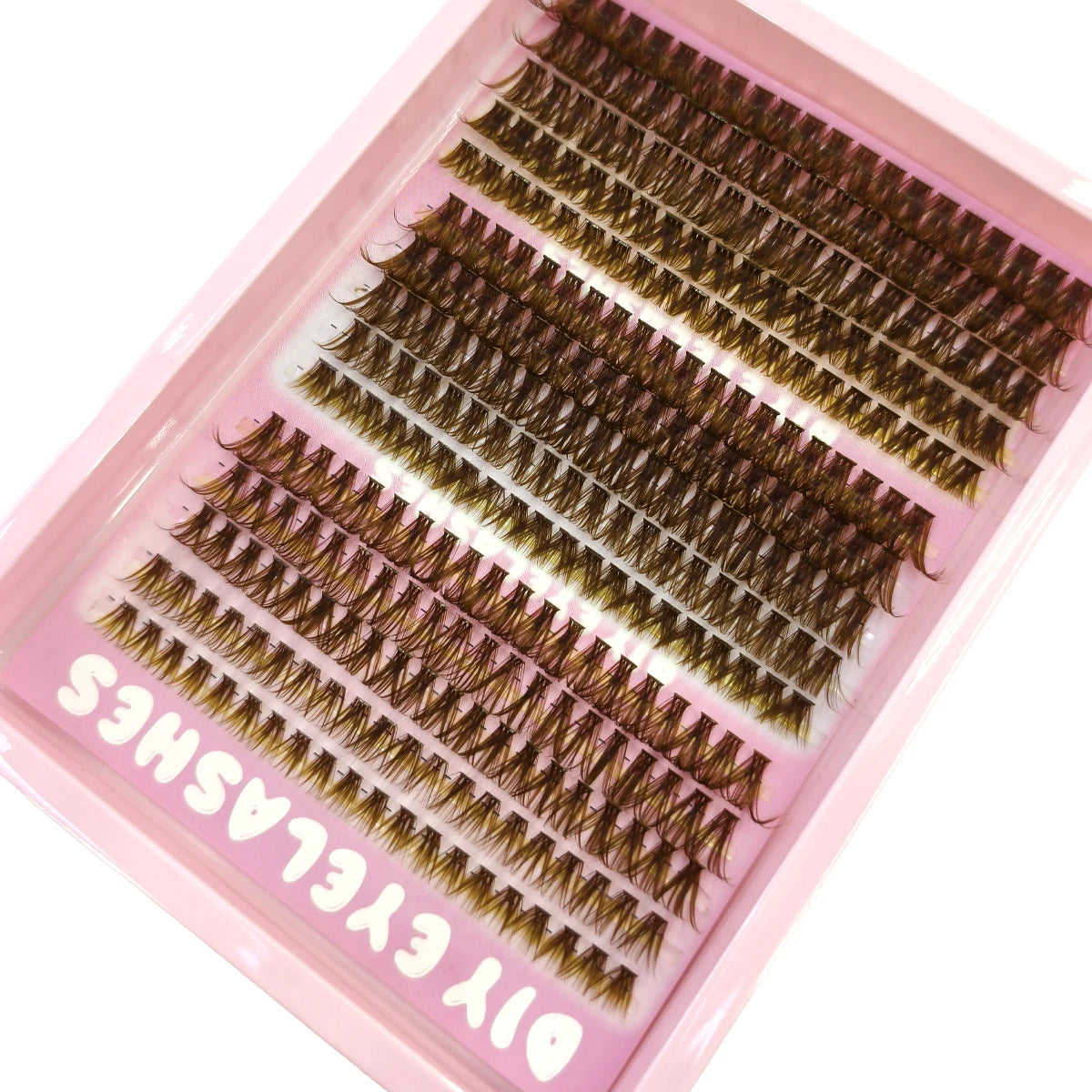 Un plateau rose contient des extensions de faux cils naturels et fins pour application DIY.