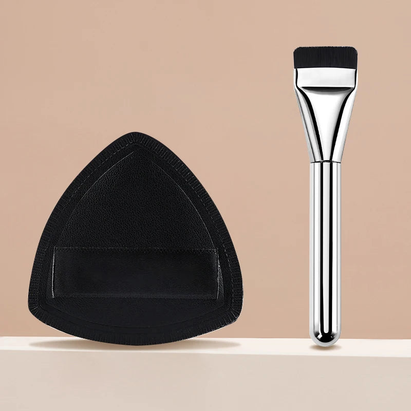 A black triangular cosmetic foundation puff brush with a silver handle.