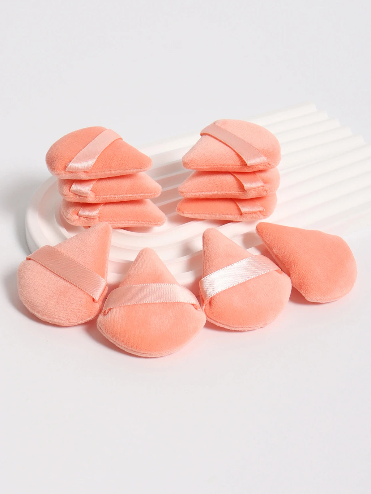 Un ensemble de puffs triangulaires roses avec des accents de ruban satiné, arrangés sur un plat blanc.