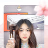 A woman is using an automatic ceramic curling iron to style her long brown hair.