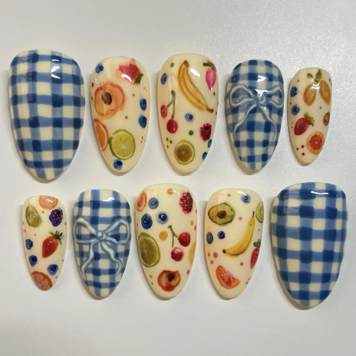A collection of 24 press-on nails featuring pink flowers and almond shapes with various fruit designs on a white background.