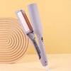 A purple electric curling iron with a heated barrel is shown against a light yellow background.