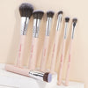 A set of seven professional makeup brushes with light pink handles and silver ferrules displayed against a neutral background