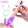 A hand holds a pink nail lamp device emitting purple light onto a fingernail for drying.