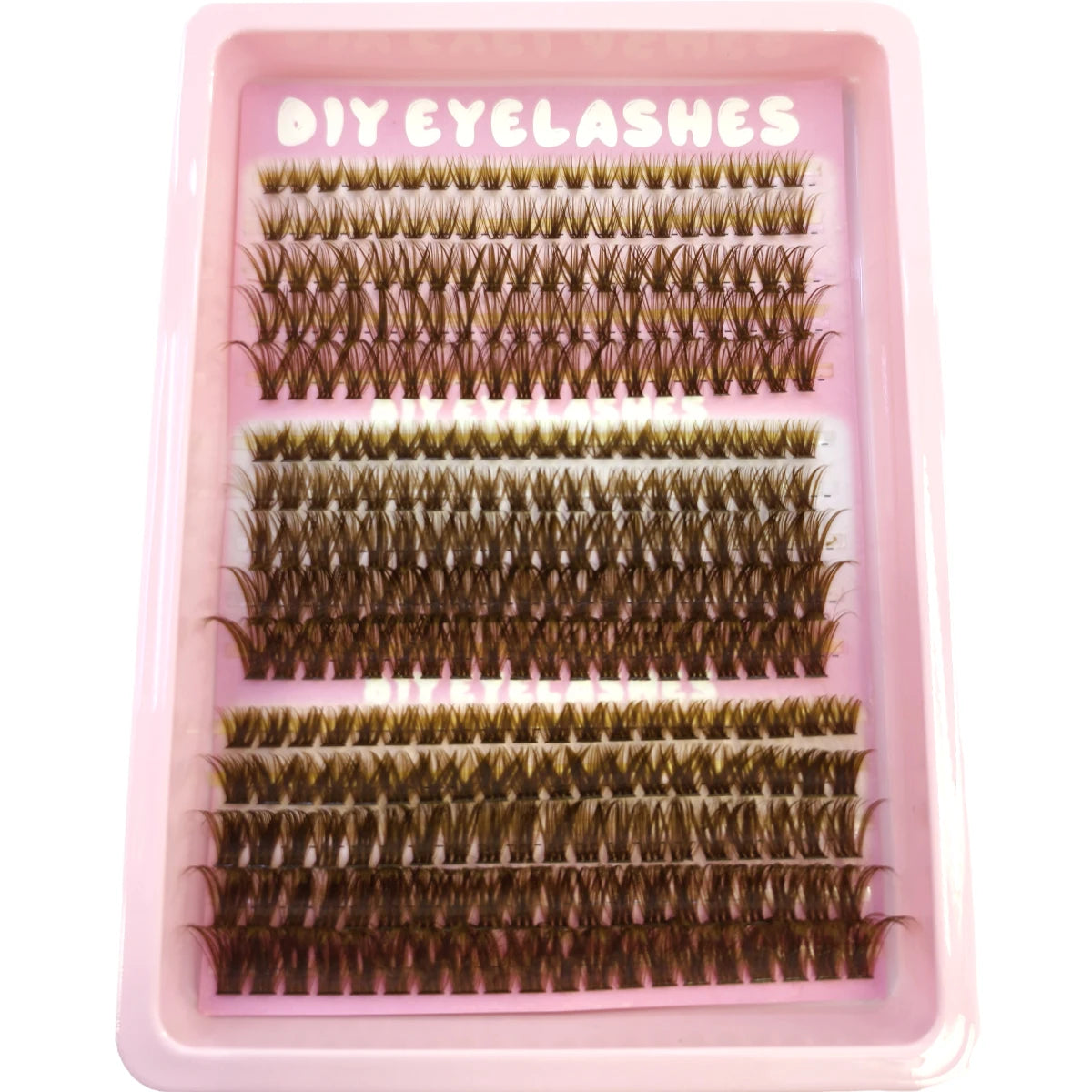Un plateau rose présentant diverses extensions de faux cils naturels et fins dans différentes nuances de brun et de vert.