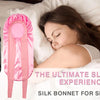 A woman is sleeping with a pink satin silk hair bonnet on her head, next to a black version.