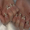 A close-up of hands displaying pink heart pearl press-on fake nails with leopard print accents and white bows.