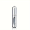 A sleek, cylindrical silver perfume atomizer bottle with a clear window is shown against a white background.