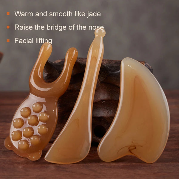 A set of smooth, translucent amber-colored facial tools for massage and lifting.