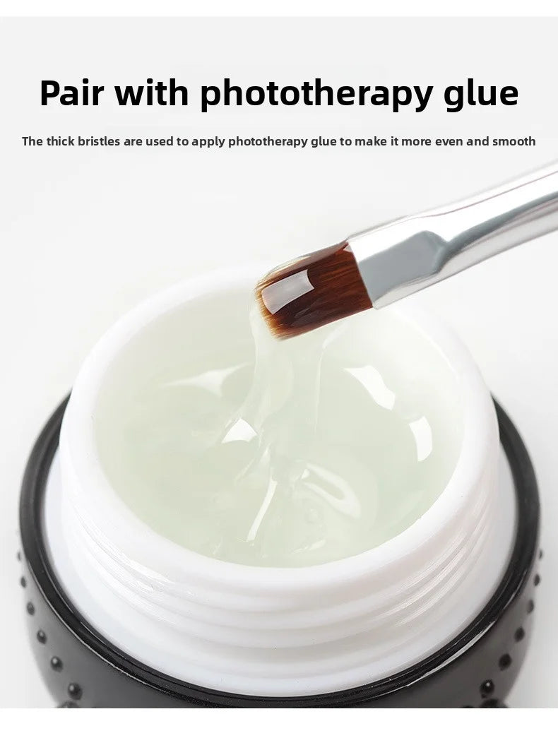 Gros plan d'un pinceau à ongles professionnel appliquant de la colle photothérapie sur une substance blanche dans un pot.