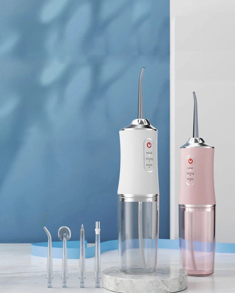 A pink and white portable USB rechargeable water flosser for dental cleaning displayed on a glass stand.
