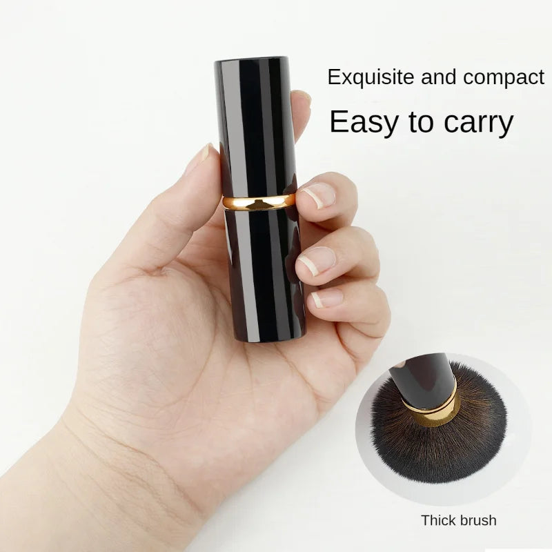 Une main tient un pinceau de maquillage rétractable, élégant et compact, avec une touche d'or, montrant sa taille et sa textu