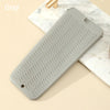 A gray heat resistant silicone mat with wavy grooves is shown on a marble surface.