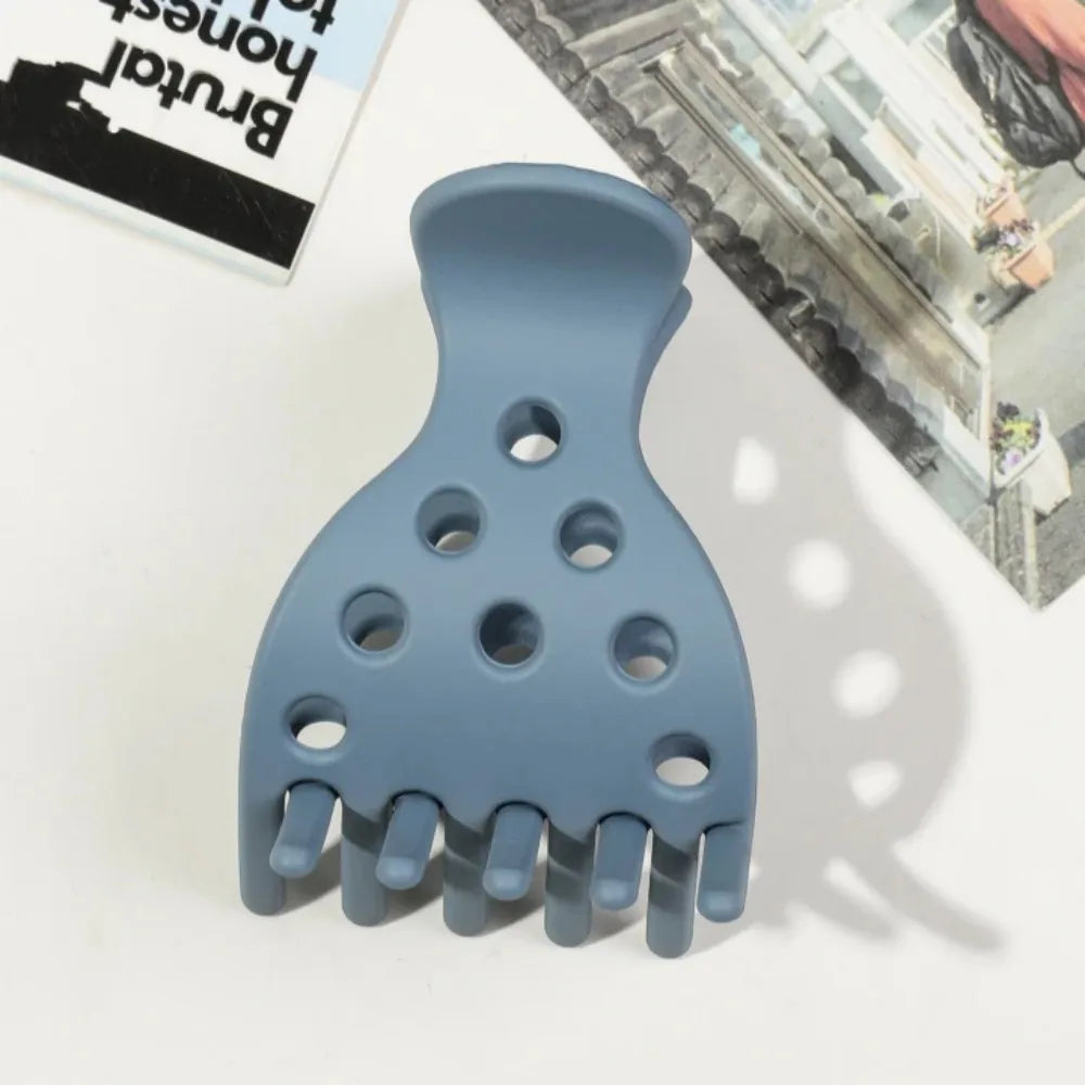 A light blue plastic root lifting hair clip with multiple prongs shown on a white surface.