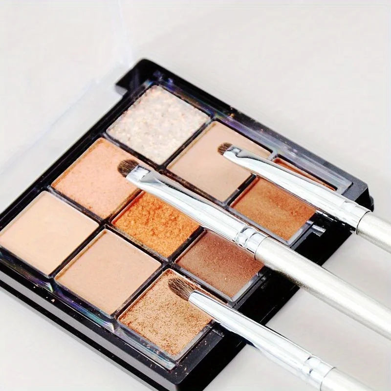 A black eyeshadow palette with various shades of brown and beige eyeshadows and brushes.